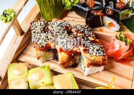 Un set colorato di sushi freschi, verdure e altri piatti sani riempiono il piatto - un pasto perfetto per il benessere. Foto Stock