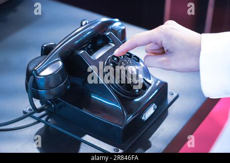 Un vecchio telefono con linea telefonica in bachelite con un dito Foto Stock