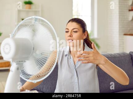 Donna, stanca di caldo tempo estivo, godendo di aria fredda soffiata in  faccia da un ventilatore elettrico Foto stock - Alamy