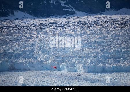 Un elicottero vola quasi al livello del mare, vicino alla faccia calvante del ghiacciaio Columbia, vicino a Valdez, Alaska. Foto Stock