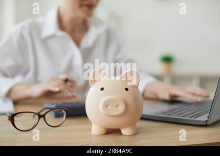 Banca di maiale in forma di maiale in background di consulente finanziario che pianifica il bilancio annuale. Foto Stock