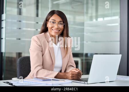 Giovane donna professionale felice di affari manager siede alla scrivania ufficio, ritratto. Foto Stock