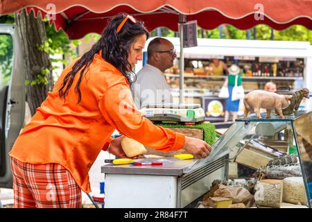 Commerciante di mercato che taglia grossi blocchi di formaggio locale - la Roche Posay, Vienne (86), Francia. Foto Stock