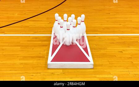 Birilli da bowling su una tavola da gioco di cornhole in una palestra per le lezioni di palestra per divertirsi. Foto Stock