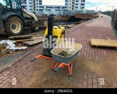 carrello per il trasporto di materiali pesanti, calcestruzzo, mattoni e sabbia. accanto alla macchina per la produzione di superfici stradali. sullo sfondo Foto Stock