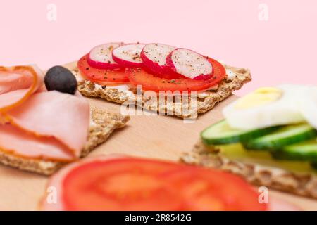 Diversi tipi di pane integrale con Prato, pomodoro, Rasth, cetriolo e formaggio. Colazione facile. Dieta alimentare. Panini veloci e sani. Croccante con gustoso ripieno. Snack dietetico sano Foto Stock