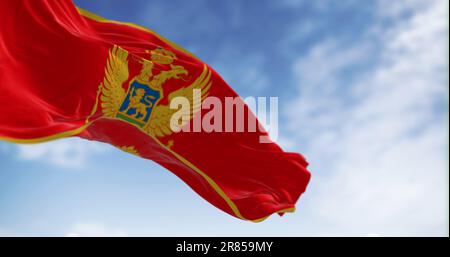 Bandiera nazionale del Montenegro che sventola nel vento in una giornata limpida. Rosso con bordo dorato e con lo stemma nazionale al centro. illus 3d. Foto Stock