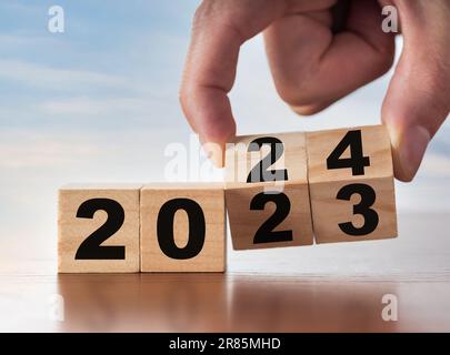 2024 concetto di business per la crescita del successo. Cubi di legno ribaltabili a mano per uomo d'affari a partire dal nuovo anno 2024 con un piano d'azione. Foto Stock