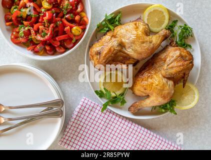 Arrostire mezzo pollo con insalata su un tavolo bianco. Vista dall'alto Foto Stock