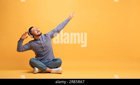 Giovane uomo asiatico felice ascoltare musica in cuffie wireless e danza Foto Stock