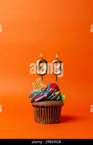 torta di compleanno con numero 93 - cupcake su sfondo arancione con candele di compleanno Foto Stock