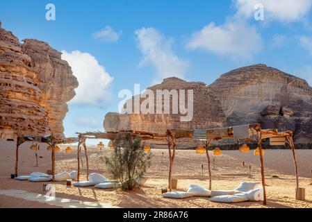 Lounge all'aperto di fronte al monolito dell'erosione della roccia degli elefanti che sorge nel deserto, al Ula, Arabia Saudita Foto Stock