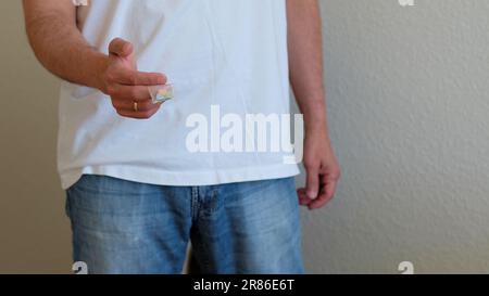 Uomo che offre pillole di ecstasy Tesla in un sacchetto di plastica; a forma di scudo con il logo Tesla; 240 milligrammi di MDMA Molly ricreativa, farmaci. Foto Stock
