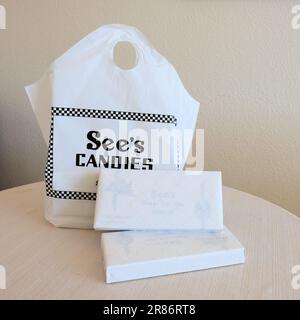 Una borsa per la spesa con il marchio SEE's Candies e scatole di cioccolato assortito avvolte in tradizionale carta da macelleria bianca per regali. Foto Stock