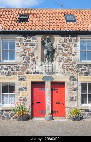 Lower Largo, Regno Unito - 9 giugno 2023: Una statua di Robinson Crusoe in un recinto recinto muro enclave o nicchia nel villaggio natale di Alexander Selkirk, a Fife, S Foto Stock