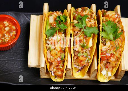 tradizionale piatto messicano di mais taco con salmone affumicato, salsa di pomodoro, avocado e panna acida Foto Stock