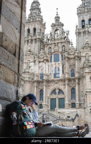 Giovane donna pellegrina leggendo un libro a Santiago de Compostela, la Coruna, Galizia, Spagna. Foto Stock