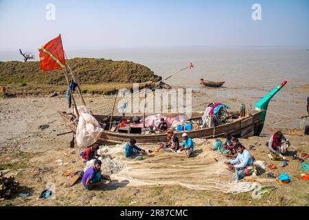 Pescatori che riparano le loro reti da pesca a sulla riva del fiume Meghna a Monpura Island in Bhola, Bangladesh Foto Stock