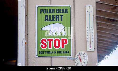 Un segnale di allarme dell'orso polare e due termometri esterni che mostrano temperature inferiori allo zero, attaccati a una parete esterna della casa nel Canada settentrionale. Foto Stock