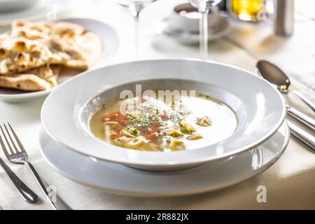 Zuppa di pollo all'italiana con tortellini, carote, prezzemolo e pizza focaccia. Foto Stock