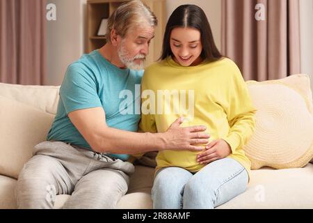 Donna incinta felice che trascorre il tempo con suo padre a casa. Reazione dei nonni al futuro nipote Foto Stock