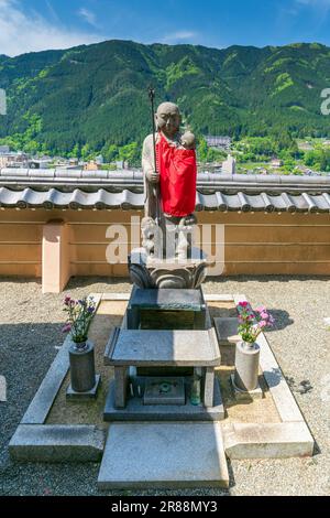 Statua del Santuario con tessuto rosso drappeggiato intorno nel tempio buddista di Onsenji a Gero, Prefettura di Gifu., Giappone. Foto Stock