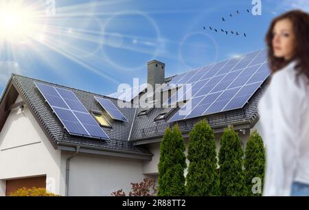 Pannelli solari su un tetto a capanna. Bella, grande casa moderna e l'energia solare, donna. Raggi del sole. Pannello fotovoltaico. Foto Stock
