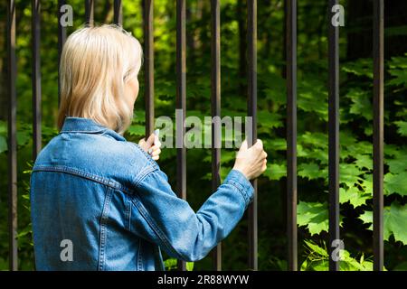 le mani femminili afferrarono le barre dietro le quali la libertà. recinzione al confine. attraversamento della frontiera statale. Foto di alta qualità Foto Stock