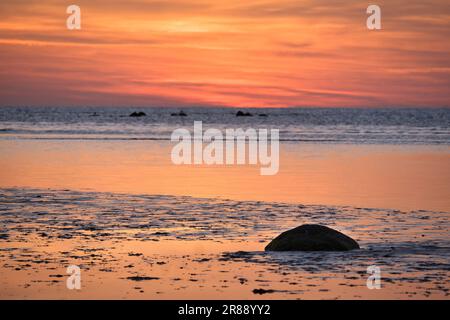 Tramonto, piccola roccia con bassa marea di fronte al mare illuminato. Onde luminose. Isola di Poel sul Mar Baltico. Foto della natura dalla costa Foto Stock