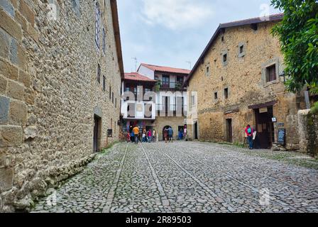 Un'antica strada acciottolata fiancheggiata da edifici vivaci è piena di gente in una pittoresca città vecchia Foto Stock