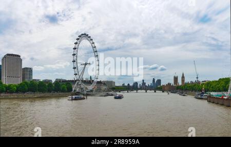 Una splendida vista aerea di una grande ruota panoramica su una riva del fiume, circondata da un ponte, sullo sfondo di cielo e alberi Foto Stock