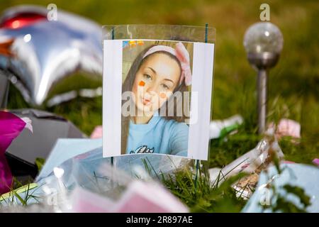 Una foto di Chloe Mitchell si trova con tributi floreali al King George's Park di Harryville, Ballymena, in ricordo della signora Mitchell. Ryan Johnston Gordon, 34 anni, da Nursery Close, Ballymena, è apparso tramite video link dal carcere di Maghaberry incaricato di assistere un delinquente per la morte di Chloe, 21 anni, che è stato visto l'ultima volta nelle prime ore di Sabato 3 giugno nel centro di Ballymena. Data immagine: Martedì 20 giugno 2023. Foto Stock