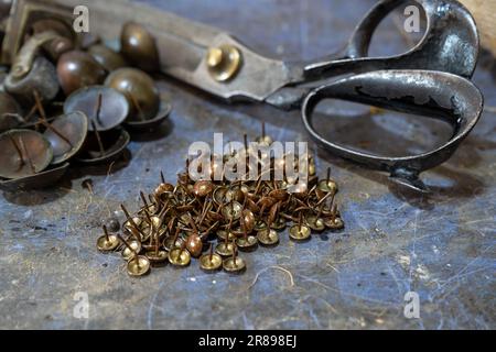 Chiodi da tappezzeria e forbici sul banco di lavoro in un'officina artigianale, spazio copia, messa a fuoco selezionata, profondità di campo ristretta Foto Stock