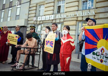 Amburgo, Germania. 20th giugno, 2023. Un attivista (3rd da sinistra) siede su un'imitazione di un presidente di tigre durante un'azione di protesta degli attori tibetani contro i crimini dei diritti umani in Tibet di fronte a un ramo della Banca della Cina presso il Rathausmarkt. Su una cosiddetta sedia della tigre, le persone sono immobilizzate durante l'interrogazione. Credit: Gregor Fischer/dpa/Alamy Live News Foto Stock