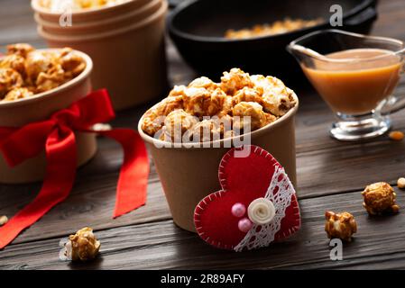 Secchielli in cartone con popcorn caramellato e decorazioni valentine su fondo da cucina Foto Stock