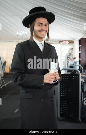 Un giovane asidico raccoglie la carità in una sinagoga tenda a Monsey, nella contea di Rockland, giugno 2023. Foto Stock