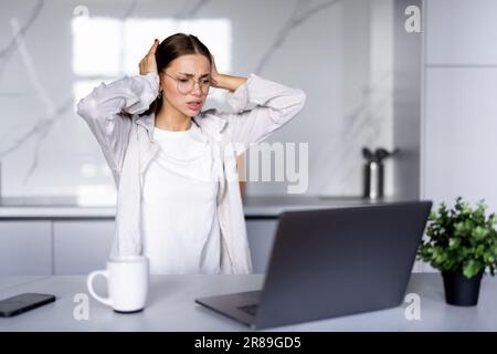 La giovane donna ha lavorato spossato di usare un notebook, avendo stress e mal di testa. Ragazza studentesca triste e infelice stanca Foto Stock