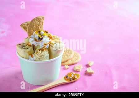 Panino gelato con torta Parchita, con crema chantilly, sciroppo di frutto della passione, su sfondo rosa Foto Stock