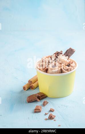 Rotolo di gelato con cioccolato e caffè, con pezzi di cioccolato e biscotti su sfondo blu Foto Stock
