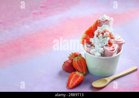 Rotolo di gelato alla fragola con panna su sfondo rosa Foto Stock