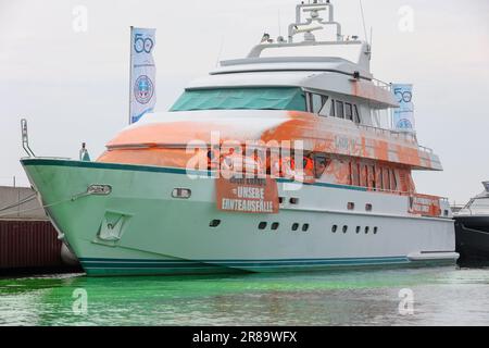 20 giugno 2023, Schleswig-Holstein, Neustadt in Holstein: Partecipanti a uno stand di protesta con striscioni su uno yacht nel porto di Neustadt. Su un banner c'è l'iscrizione 'il vostro lusso = i nostri crop fails'. Gli attivisti del gruppo Letzte Generation hanno spruzzato una barca con vernice a Neustadt in Holstein il martedì. Come parte dell'azione, anche l'acqua nel porticciolo era colorata di verde con una tintura. Foto: --/dpa Foto Stock