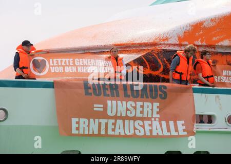 20 giugno 2023, Schleswig-Holstein, Neustadt in Holstein: Partecipanti a uno stand di protesta con striscioni su uno yacht nel porto di Neustadt. Su un banner c'è l'iscrizione 'il vostro lusso = i nostri crop fails'. Gli attivisti del gruppo Last Generation hanno spruzzato una barca con vernice a Neustadt in Holstein il martedì. Foto: --/dpa Foto Stock