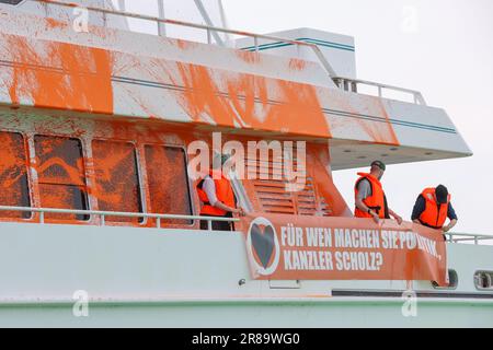 20 giugno 2023, Schleswig-Holstein, Neustadt in Holstein: Partecipanti a uno stand di protesta con striscioni su uno yacht nel porto di Neustadt. Un banner recita: "Per chi fai politica, Cancelliere Scholz?”. Gli attivisti del gruppo Letzte Generation hanno spruzzato una barca con vernice a Neustadt in Holstein il martedì. Foto: --/dpa Foto Stock