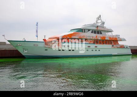 20 giugno 2023, Schleswig-Holstein, Neustadt in Holstein: Partecipanti a uno stand di protesta con striscioni su uno yacht nel porto di Neustadt. Su un banner c'è l'iscrizione 'il vostro lusso = i nostri crop fails'. Gli attivisti del gruppo Letzte Generation hanno spruzzato una barca con vernice a Neustadt in Holstein il martedì. Come parte dell'azione, anche l'acqua nel porticciolo era colorata di verde con una tintura. Foto: --/dpa Foto Stock