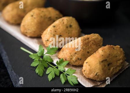 Bolinhos de bacalhau, molto famoso nella gastronomia portoghese. Gnocchi fritti, gnocchi di merluzzo, pesce, bacalao bunuelos. Torta di merluzzo su sfondo scuro. Foto Stock