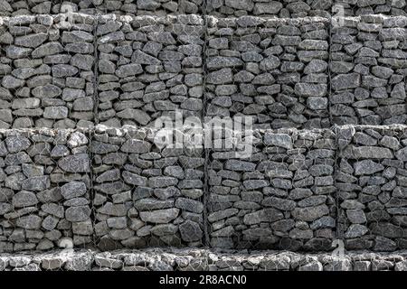 Struttura di un muro di gabione, gabbie d'acciaio riempite di rocce Foto Stock