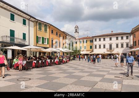 Una pittoresca piazza piena di ristoranti, caffetterie e negozi nella storica Lazise, Lago di Garda, Italia, Europa Foto Stock