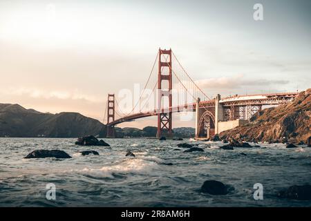 Il Golden Gate Bridge si estende su un tranquillo corpo d'acqua durante un tramonto ipnotico Foto Stock