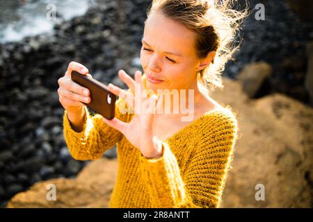 Bella, giovane donna che scatta foto con il suo smartphone durante le sue vacanze Foto Stock