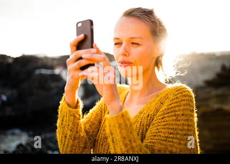 Bella, giovane donna che scatta foto con il suo smartphone durante le sue vacanze Foto Stock